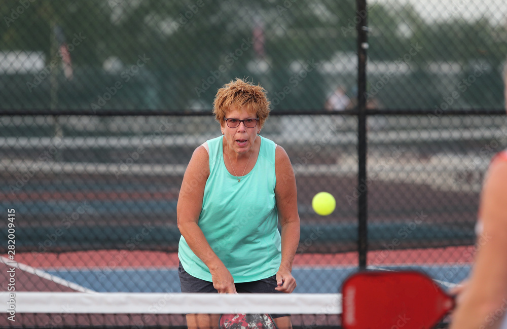 A senior woman plays pickleball