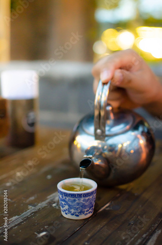 Pouring tea. Chinese tradition. On wooden table. Blur bokeh in background.