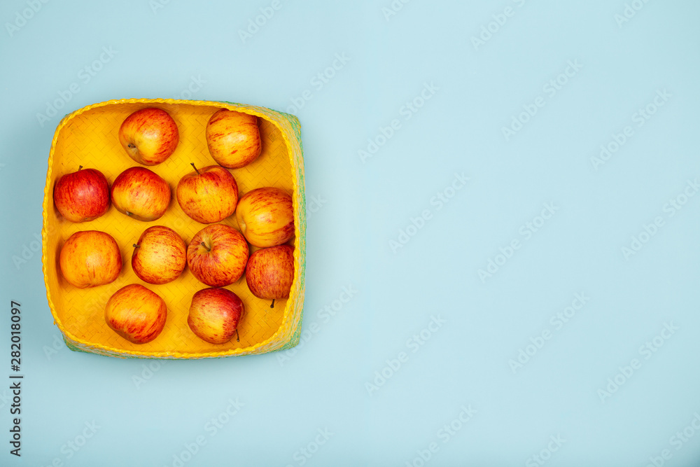 Apples in yellow baskets over a light blue background with large copy space. Apples in yellow baskets over a light blue background with large copy space.