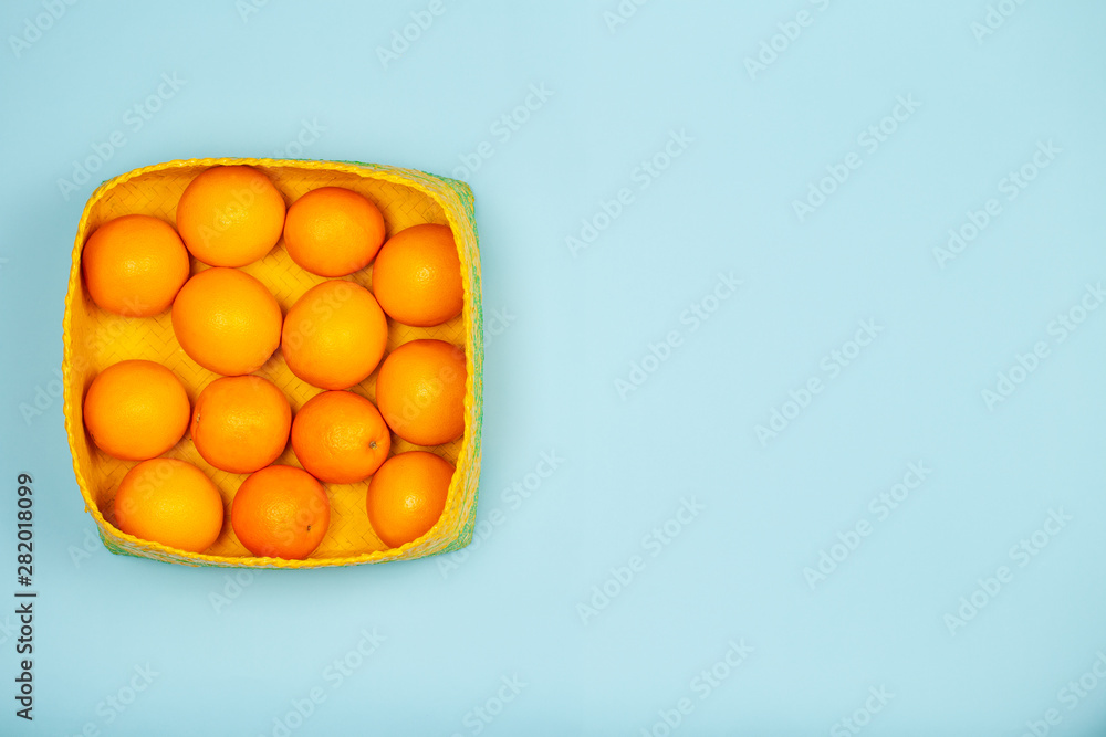 Oranges in yellow baskets over a light blue background with large copy space. Oranges in yellow baskets over a light blue background with large copy space.