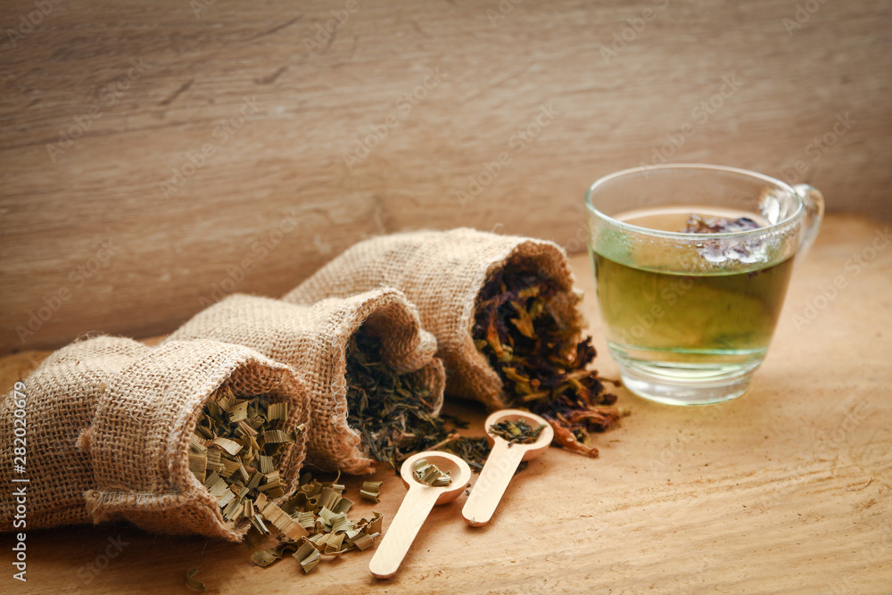 Healthy nourishing herbs are in brown sack bags. Wooden spoon and clear glass placed on the side Healthy nourishing herbs are in brown sack bags. Wooden spoon and clear glass placed on the side
