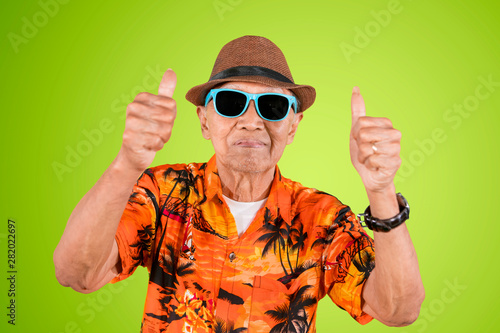 Senior male tourist showing thumbs up on studio