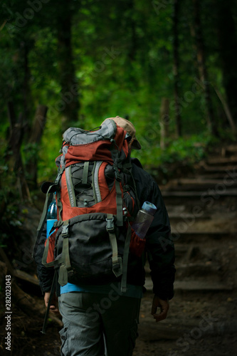man walking through the forest with a backpack