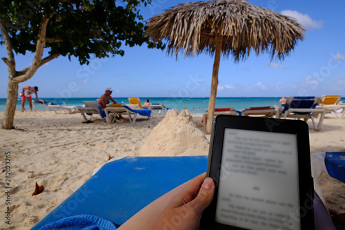 A lady reading electronic book on a beach in a sunny day