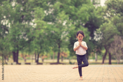 Little cute asian girl practicing yoga pose on a mat in park, Healthy and exercise concept