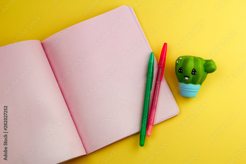 Fotografie notebook with empty sheets, pencils and cute cactus eraser on yellow background,