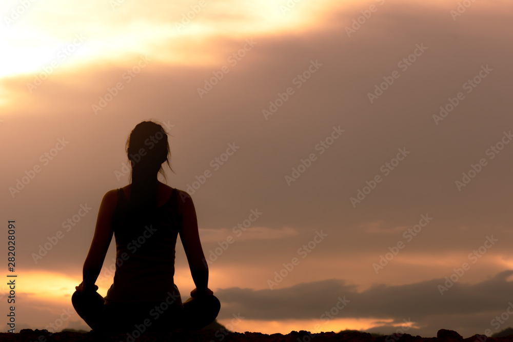 silhouette fitness girl practicing yoga on mountain