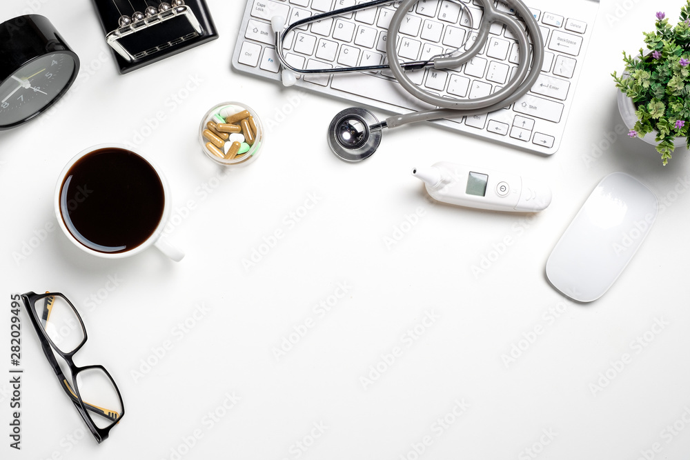 White doctors desk with Electronic thermometer, stethoscope and office supplies. Top view with copy space.