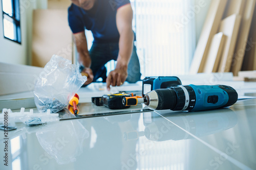Tableau sur toile Service man assembling furniture for customer, Delivery service furniture store and assembling for buyer