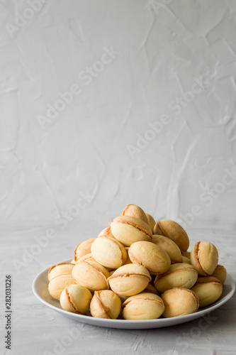 Homemade cookies in the form of nuts with boiled condensed milk on a gray table. Side view, copy space, minimalism