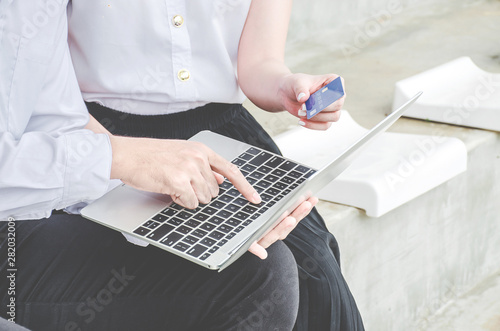 couple of friend young man and woman student in school uniform Thailand style sitting at university holding discount credit card in hand paying for shopping online at tablet,Youth casual lifestyle