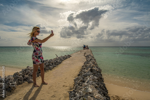 Blonde girl is taking a selfie at a pier on the beach of the Mexican Caribbean in Cozumel photo
