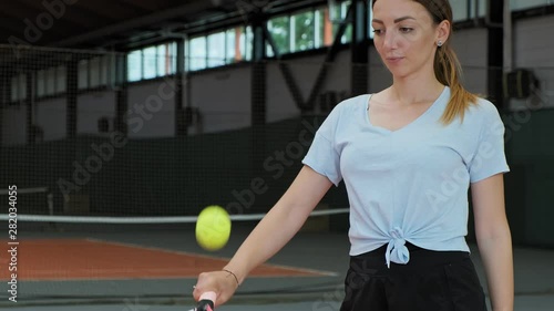Young woman doing keepy-uppies with tennis ball and racket. Close-up view of young female bounce tennis ball photo