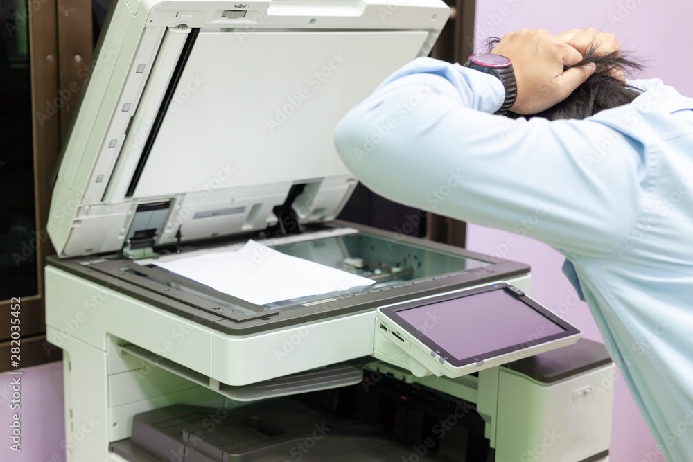 Men press the button of the copier. Man copying paper from Photocopier
