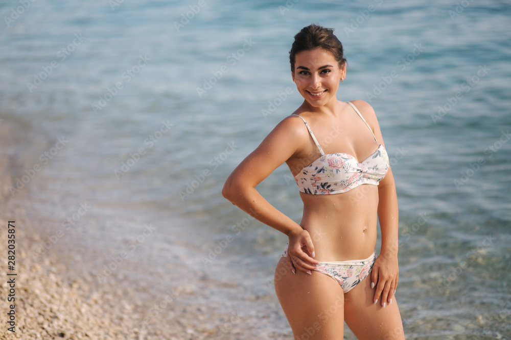 Attractive young woman walking on the beach in bikini Attractive young woman walking on the beach in bikini