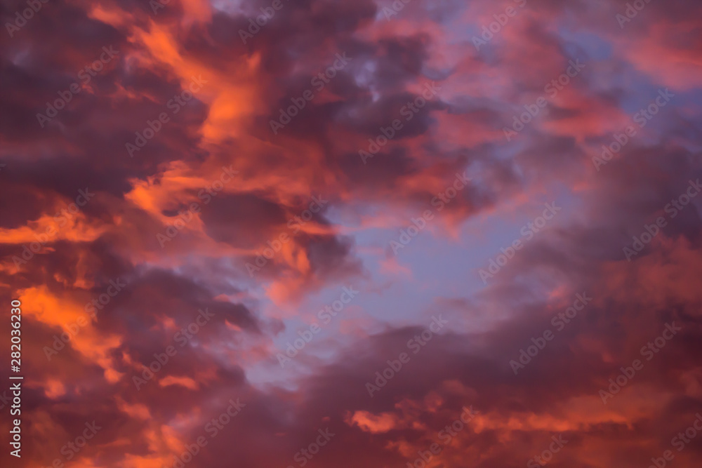 Fototapeta premium The bright orange sun rises against the backdrop of purple clouds