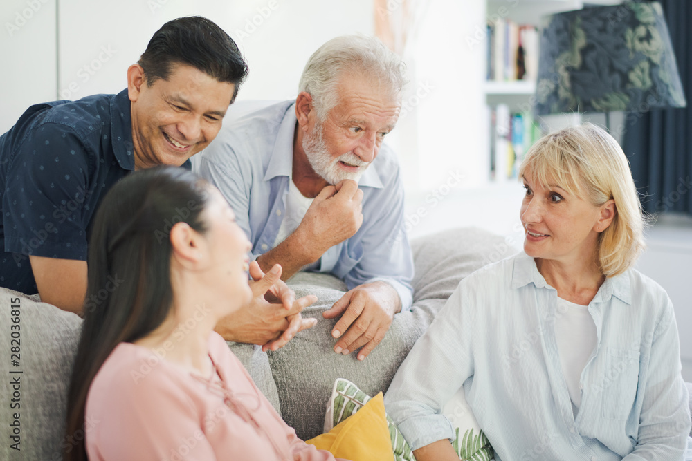 Fototapeta premium Group of positive seniors European and Asia are talking which sitting on sofa at retirement home. Retired people are discuss which smiling and felling happy.