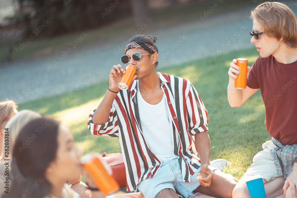 Obraz premium Two boys eating on picnic with their groupmates.