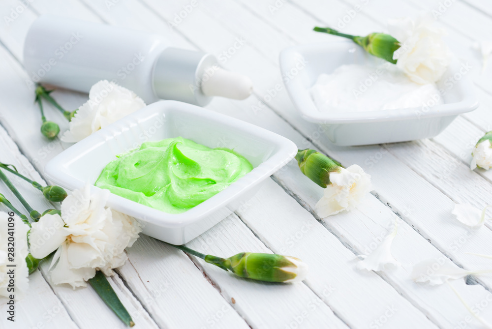 cosmetic creams, perfume in pipette and white flowers on bright wooden cosmetic creams, perfume in pipette and white flowers on bright wooden