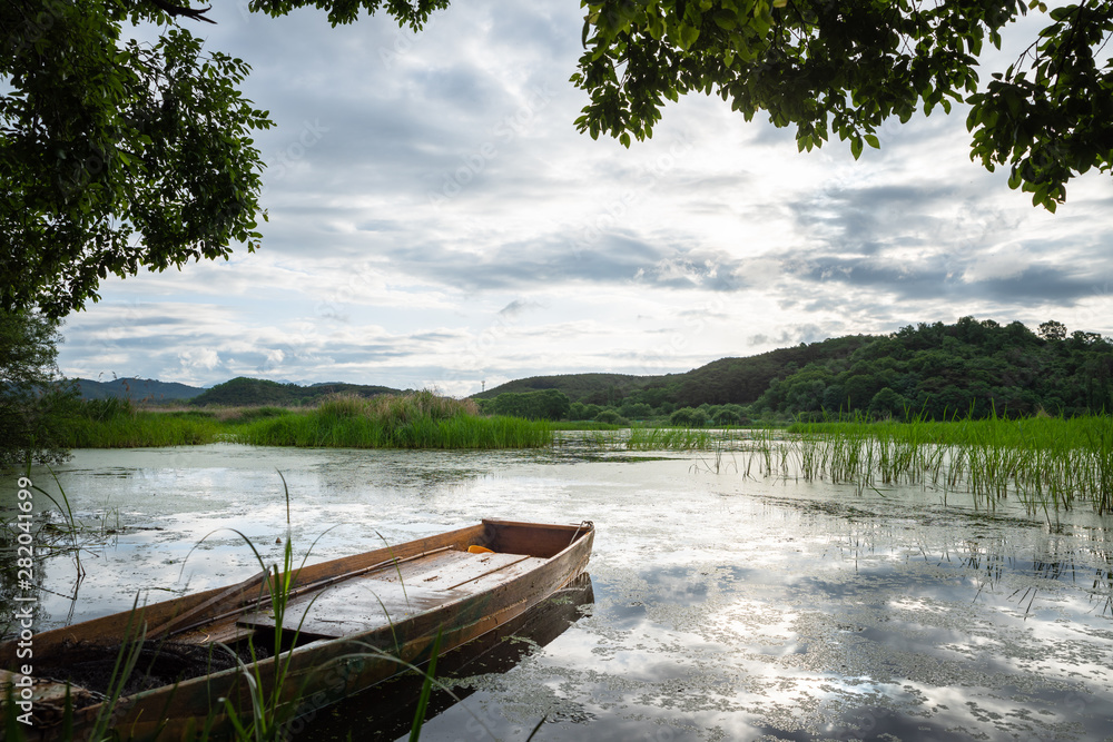 a lake with a boat floating in the sky full of clouds and reflection of the sky a lake with a boat floating in the sky full of clouds and reflection of the sky