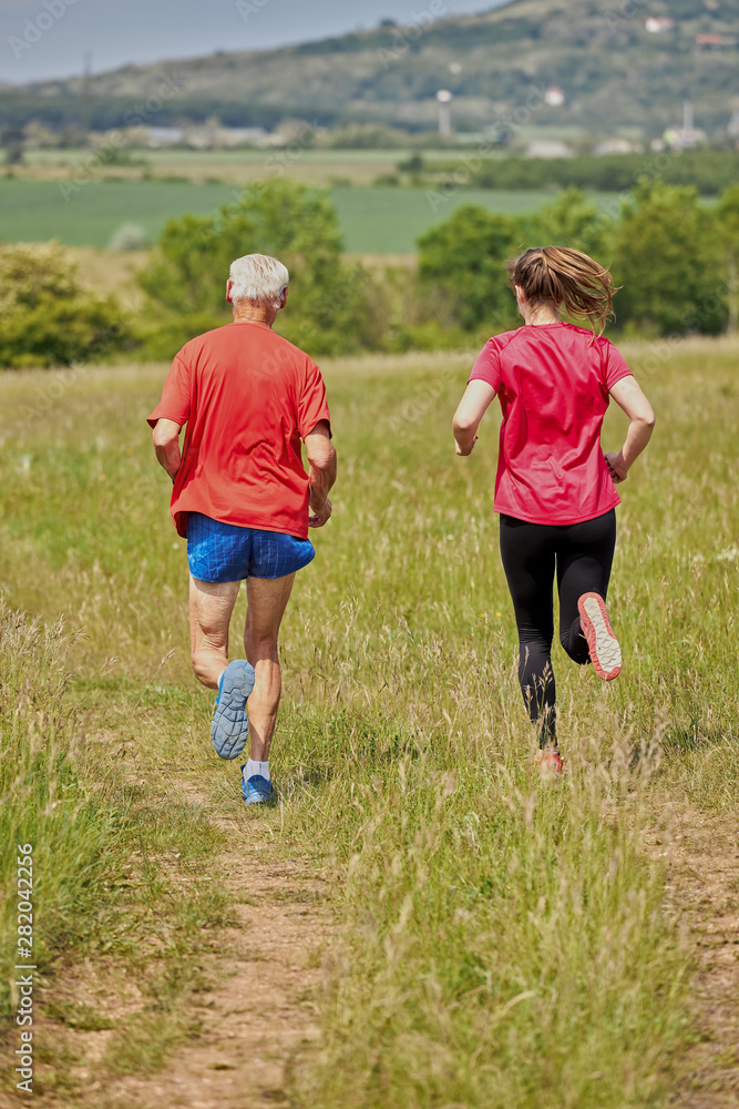 Senior man and his grandchild running on the meadow Senior man and his grandchild running on the meadow
