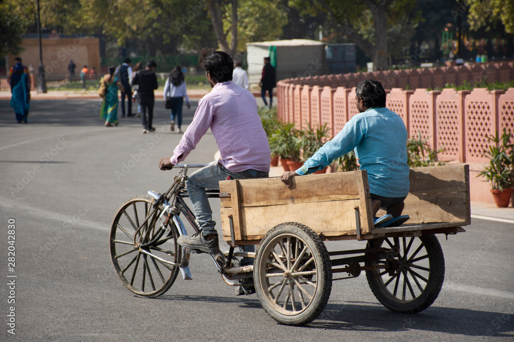Indian and foreign people worker bike bicycle and use tricycle carrying and delivery product on the road of rural at Delhi city in New Delhi, India