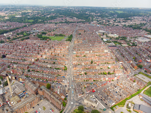 Aerial photo of the Harehills area of the Leeds City Centre in West Yorkshire in the UK and showing rows of terrace houses and urban streets, taken on a bright sunny day.