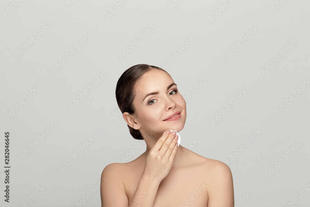 Beauty portrait of a cheerful young topless woman removing face make-up with a cotton pad Beauty portrait of a cheerful young topless woman removing face make-up with a cotton pad