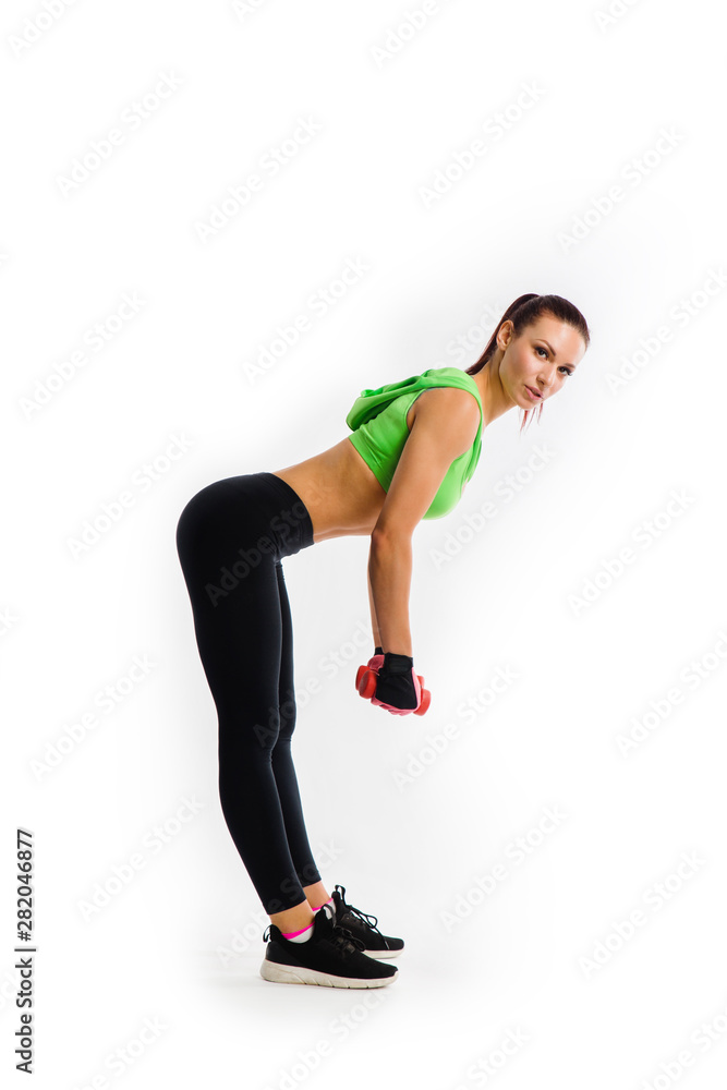 Sporty girl doing exercises with dumbbells at biceps on white background.