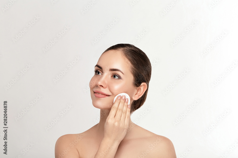 Beauty portrait of a cheerful young topless woman removing face make-up with a cotton pad Beauty portrait of a cheerful young topless woman removing face make-up with a cotton pad