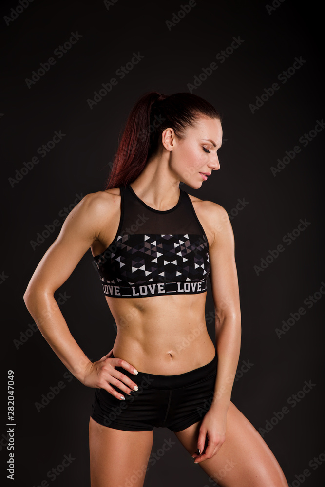 Naklejka premium Attractive young woman in sportswear posing on black background
