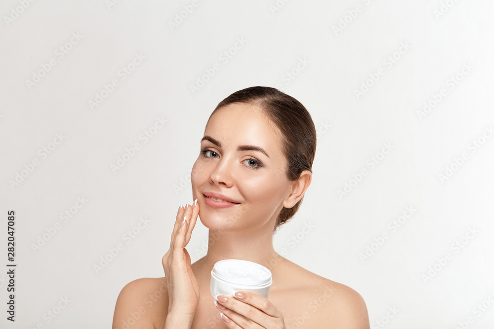 Beautiful woman with nature makeup smiling. Beauty portrait of female face holding and applying cosmetic cream. Skin care. Cosmetology, beauty and spa. Beautiful woman with nature makeup smiling. Beauty portrait of female face holding and applying cosmetic cream. Skin care. Cosmetology, beauty and spa.