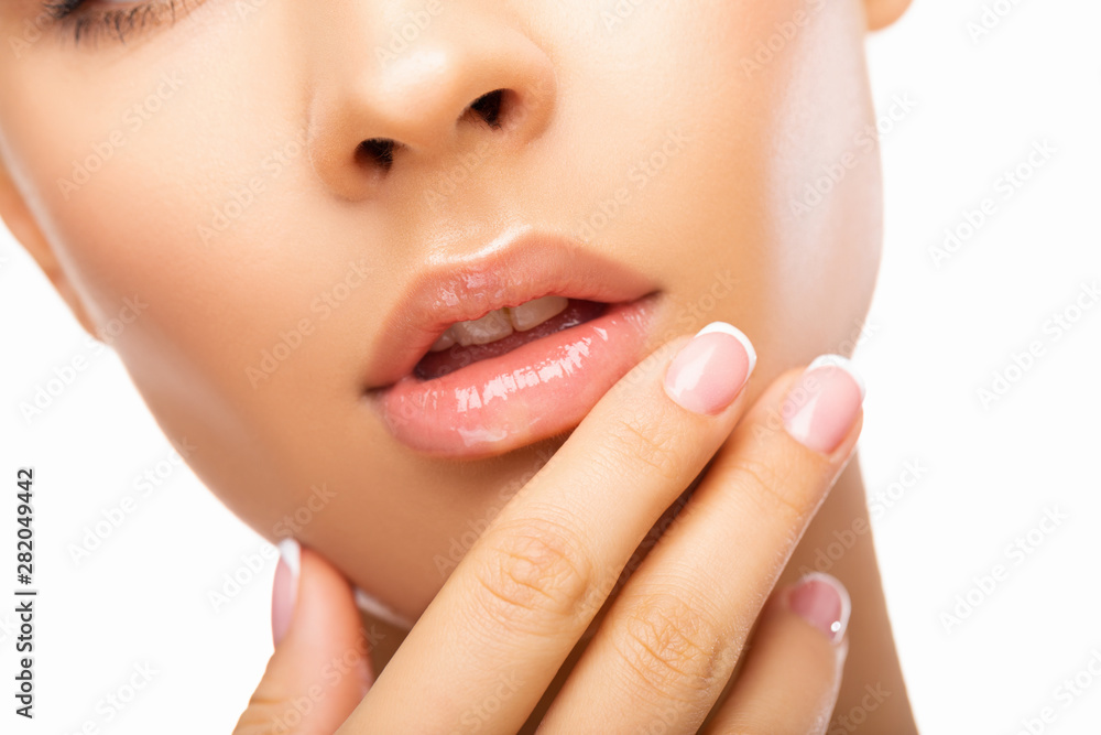 Fototapeta premium Close up beautiful Lips. Beauty Fashion woman lips with natural Makeup. shine lipstick. isolated. Closeup mouth Nude Colors lacquered model touches her lips with her hand. Make up. 