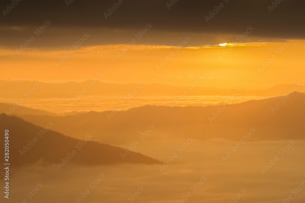 Mountain view misty morning of top hills around with sea of mist in valley and yellow sun light with cloudy sky background, sunrise at Pha Tang, Chiang Rai, northern of Thailand. Mountain view misty morning of top hills around with sea of mist in valley and yellow sun light with cloudy sky background, sunrise at Pha Tang, Chiang Rai, northern of Thailand.