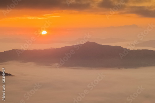 Mountain view misty morning of top hills around with sea of mist in valley and yellow sun light with cloudy sky background, sunrise at Pha Tang, Chiang Rai, northern of Thailand.