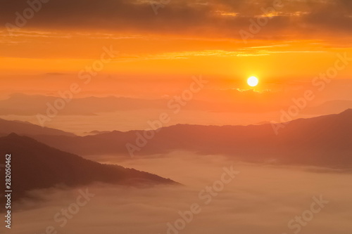 Mountain view misty morning of top hills around with sea of mist in valley and yellow sun light with cloudy sky background, sunrise at Pha Tang, Chiang Rai, northern of Thailand.
