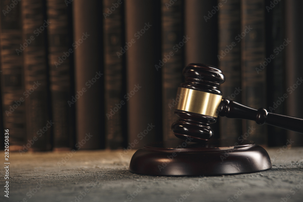 Law concept - Open law book with a wooden judges gavel on table in a courtroom or law enforcement office on black background. Law concept - Open law book with a wooden judges gavel on table in a courtroom or law enforcement office on black background.