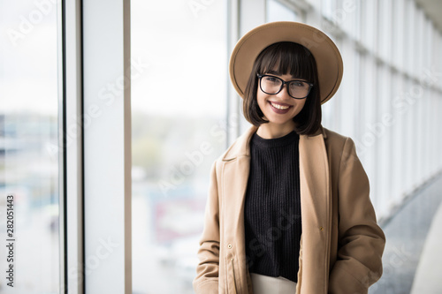 Attractive young businesswoman wearing coat and hat, glasses staring thoughtfully through office windows Free Download Attractive young businesswoman wearing coat and hat, glasses staring thoughtfully through office windows - GFXLoad