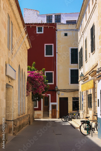 Fototapeta Naklejka Na Ścianę i Meble -  Street of Ciutadella town with colorful facades and bougainvillea in bloom, Menorca, Spain