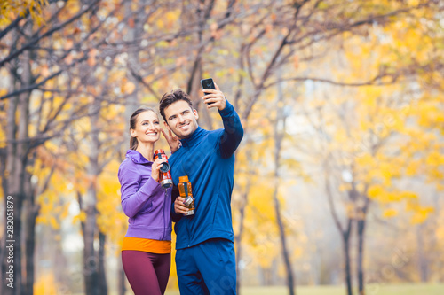 Athletic fitness couple taking selfie with their phone for social media