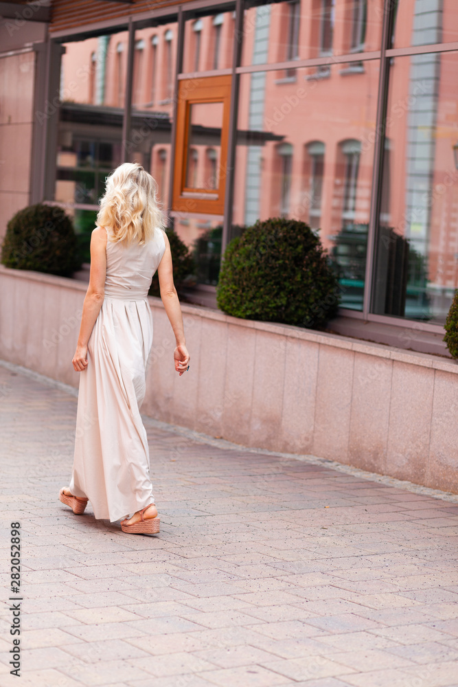 Obraz premium A blonde girl of European appearance in an evening dress poses in the city