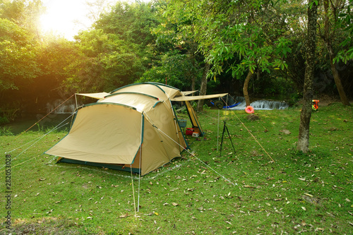 camping tent on stream and waterfall with tree in green jungle or forest for summer holiday relax and vacation travel trip with trekking and picnic on meadow or grass at Huai Mae Khamin Waterfall