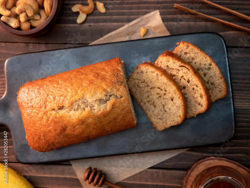 Homemade banana bread pound sliced with cashew nuts and honey on wooden table.