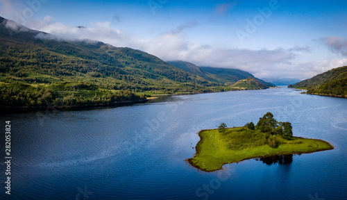 aerial view of loch leven near kinlochleven and glen coe in the argyll region of the highlands of scotland with a green island in the foreground and calm blue waters with misty mountains