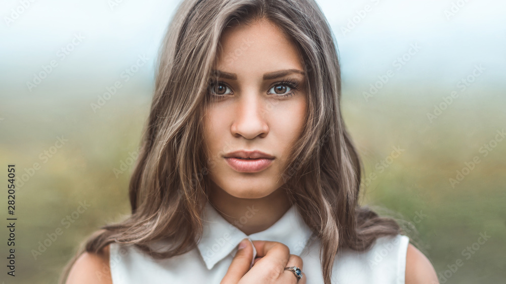 Fototapeta premium Dramatic portrait of a girl with frightened eyes against the morning mist. Close-up looking at the camera.