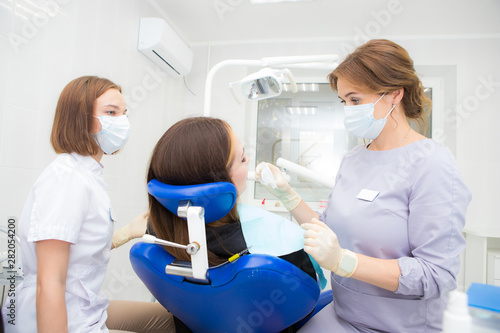 a woman dentist with an assistant treats a tooth to a woman in a modern dental clinic