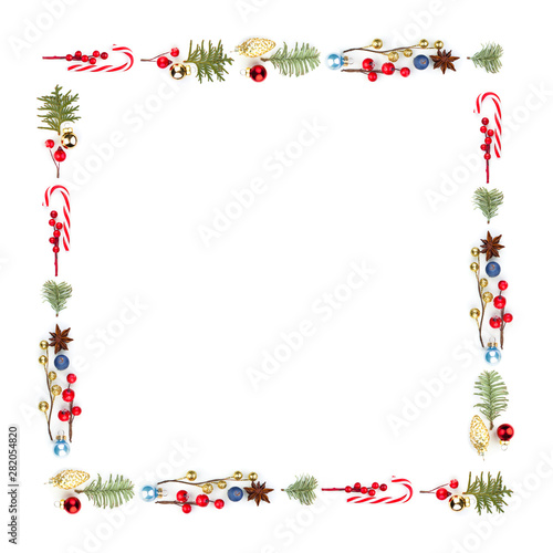 Colorful Christmas square composition frame with Xmas lollipop, red holly berries, golden decor and green fir branch isolated on white background. Xmas flat lay top view