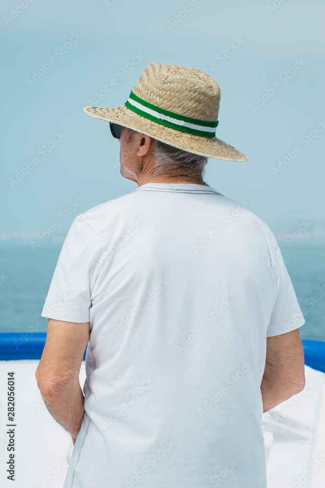 Old man with sunglasses and hat travel by boat during his vacation. Blur background of the sea and blue sky. Old man traveling. Old man with sunglasses and hat travel by boat during his vacation. Blur background of the sea and blue sky. Old man traveling.