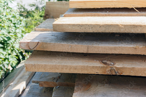 wooden planks lie in rows, sunny weather. a pile of wooden slats for the floor or ceiling are on the ground. environmentally friendly wood for construction.