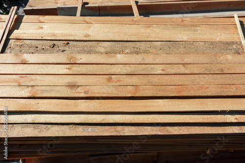 rough wooden boards lie in rows lie on the construction site. building materials for the construction of the fence. stacked wood.